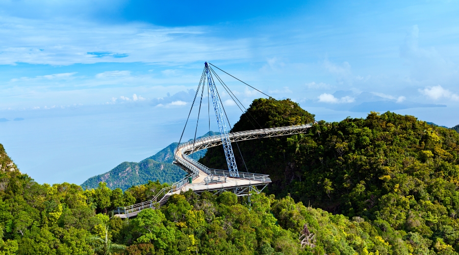 Curved Langkawi Sky Bridge stretching above green mountains with panoramic views of the Andaman Sea.